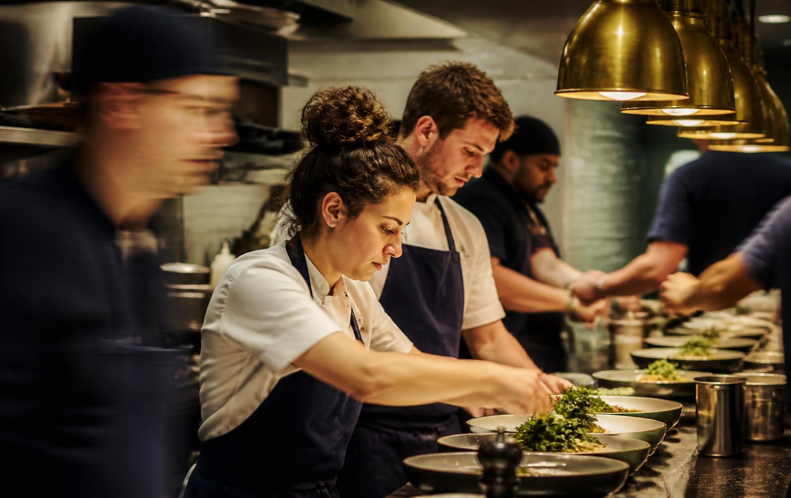 Kitchen crew plating dishes on the service line at Rumsey Tavern, a restaurant in Shepherdstown